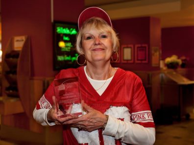 A smiling woman wearing a WSU Cougars jersey holding a glass award.