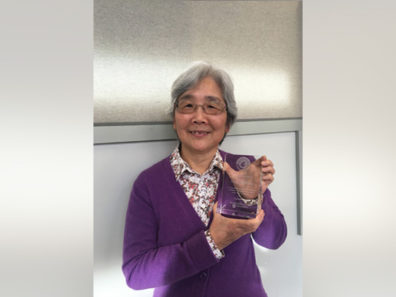 A smiling woman holding a glass award.
