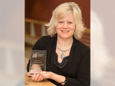 A smiling woman holding a glass award.