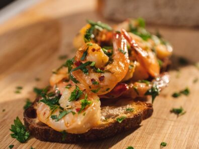 Cooked shrimp on toasted bread with green herbs.
